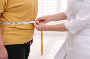 Doctor Measuring Female Patient's Waist During Weight Loss Consultation