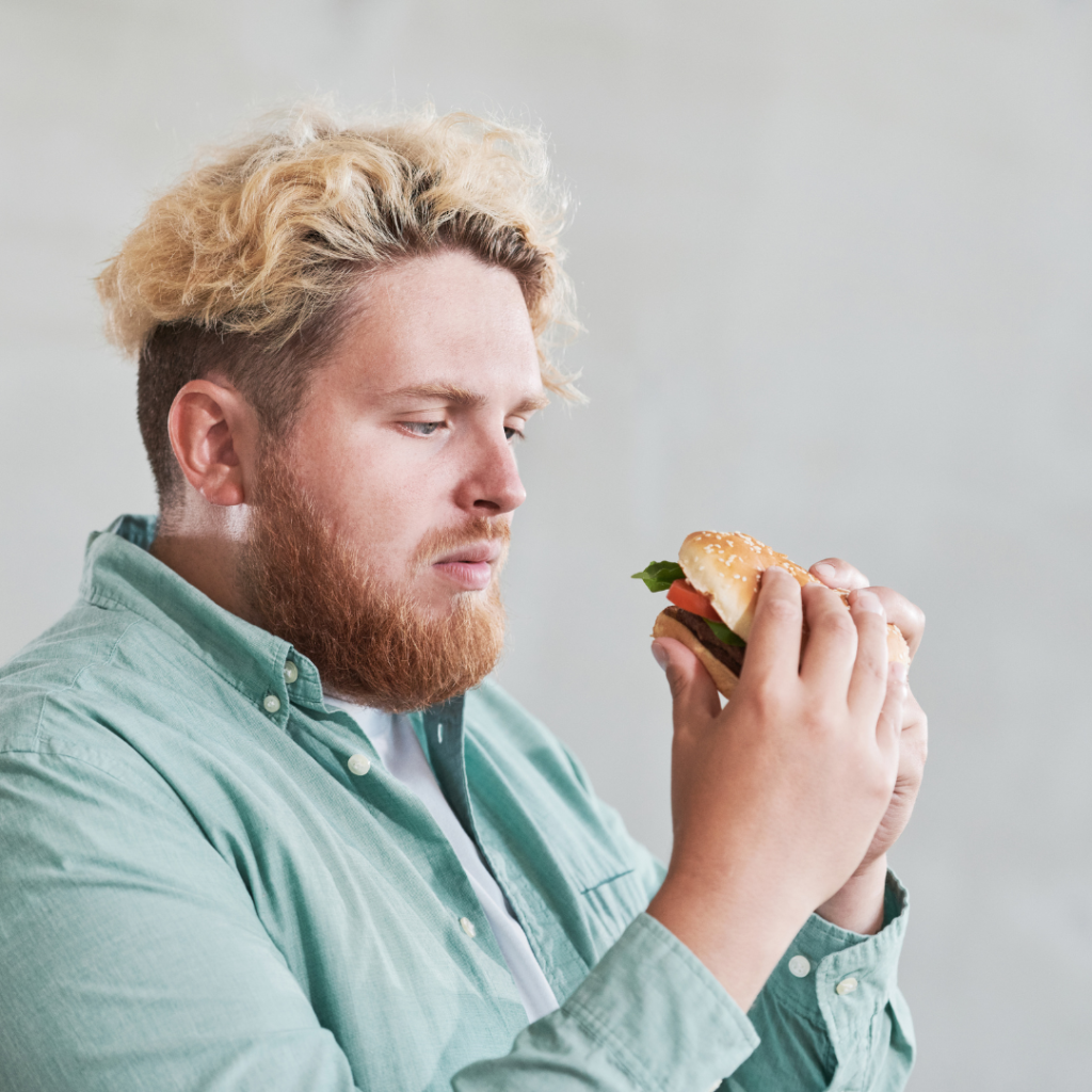 Over Weight Man Thinking Twice About Eating the Burger In his Hands